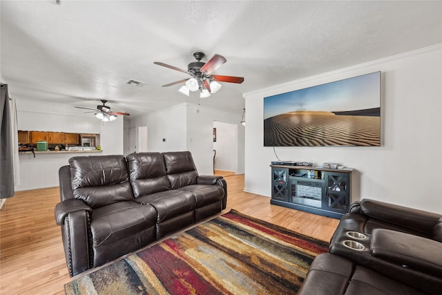 living room featuring light wood-style floors, visible vents, and ceiling fan