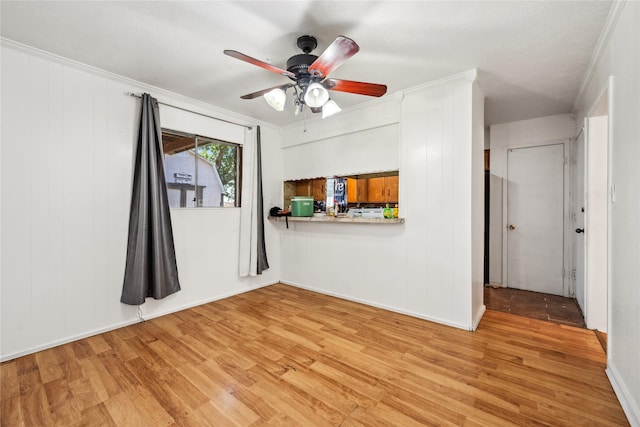 unfurnished living room with crown molding, light wood-style flooring, a ceiling fan, and baseboards