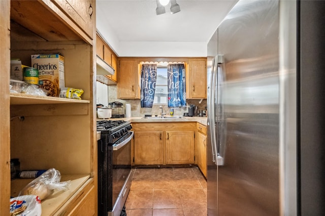 kitchen with range with gas cooktop, a sink, light countertops, freestanding refrigerator, and under cabinet range hood