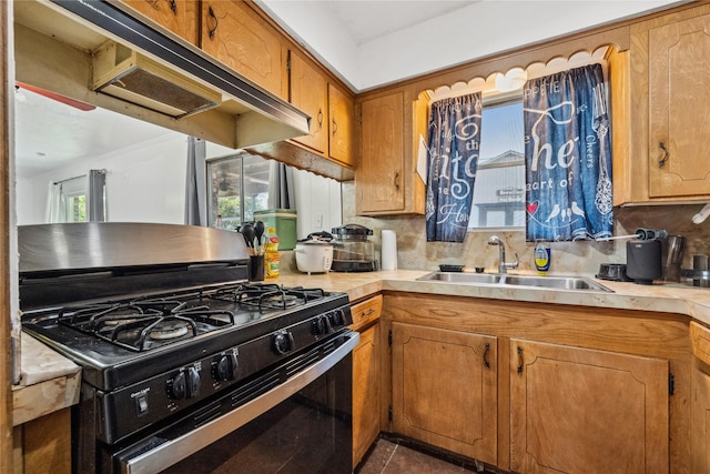 kitchen featuring black gas stove, tasteful backsplash, light countertops, brown cabinets, and a sink