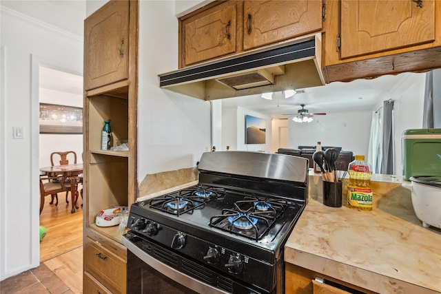 kitchen featuring brown cabinetry, light countertops, gas stove, and under cabinet range hood