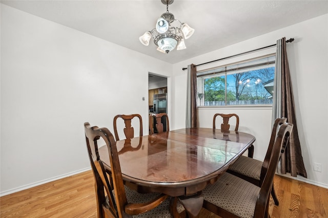 dining room featuring baseboards, light wood-type flooring, and a notable chandelier