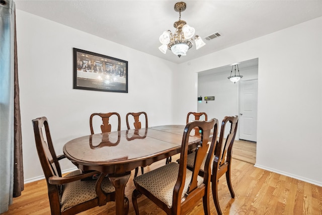 dining room featuring light wood-type flooring, an inviting chandelier, baseboards, and visible vents