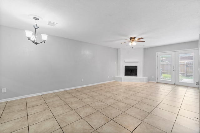 unfurnished living room featuring visible vents, light tile patterned floors, baseboards, a fireplace with raised hearth, and ceiling fan with notable chandelier