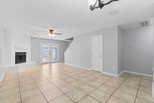 unfurnished living room with light tile patterned floors, a ceiling fan, a brick fireplace, and visible vents