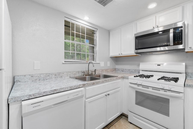kitchen featuring white appliances, recessed lighting, light countertops, white cabinets, and a sink