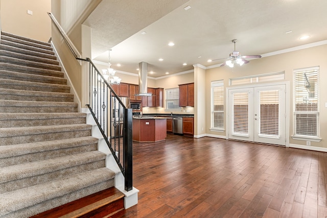 interior space featuring dark wood-style flooring, crown molding, stairs, and ceiling fan with notable chandelier