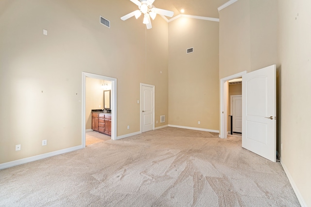 empty room with visible vents, a high ceiling, ceiling fan, and light colored carpet