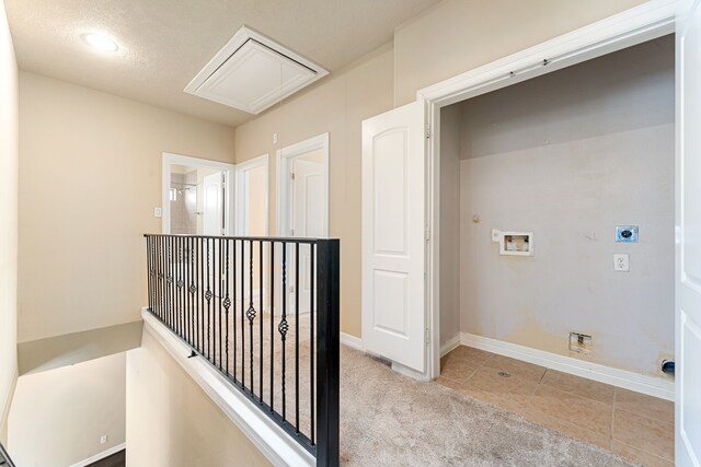 hall featuring an upstairs landing, attic access, tile patterned flooring, baseboards, and carpet flooring