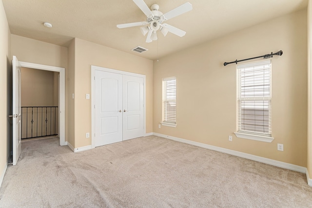 unfurnished bedroom with carpet, a closet, a ceiling fan, and baseboards