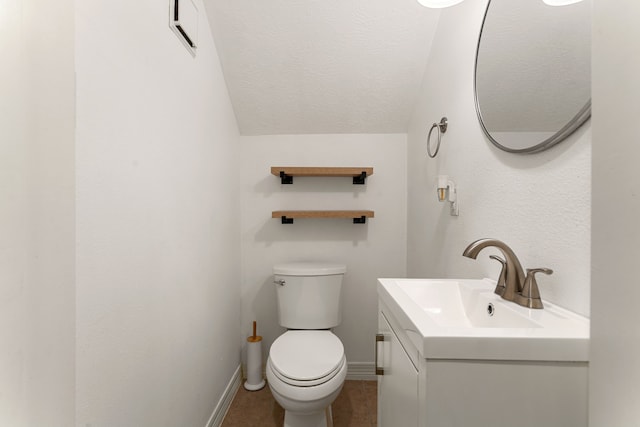 bathroom with vaulted ceiling, a textured ceiling, vanity, baseboards, and toilet
