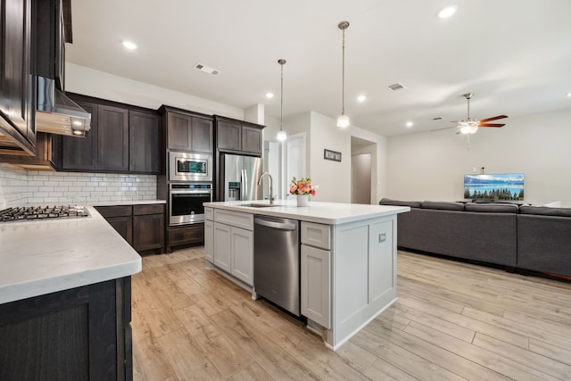 4290 Orchard Pass Dr, Spring, TX 77386 - kitchen with stainless steel appliances, wall chimney exhaust hood, backsplash, light wood-type flooring, and a ceiling fan