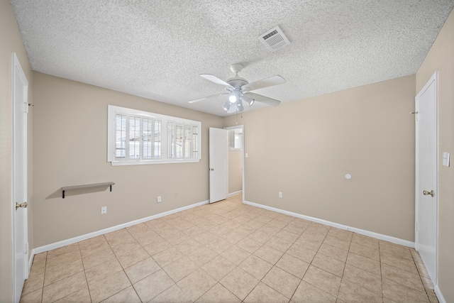 tiled empty room featuring a textured ceiling, ceiling fan, baseboards, and visible vents