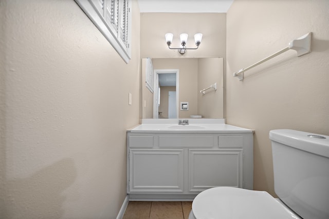 half bath with toilet, vanity, tile patterned floors, and baseboards