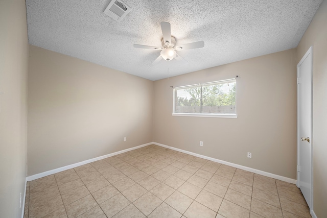 empty room with a textured ceiling, visible vents, baseboards, light tile patterned flooring, and a ceiling fan