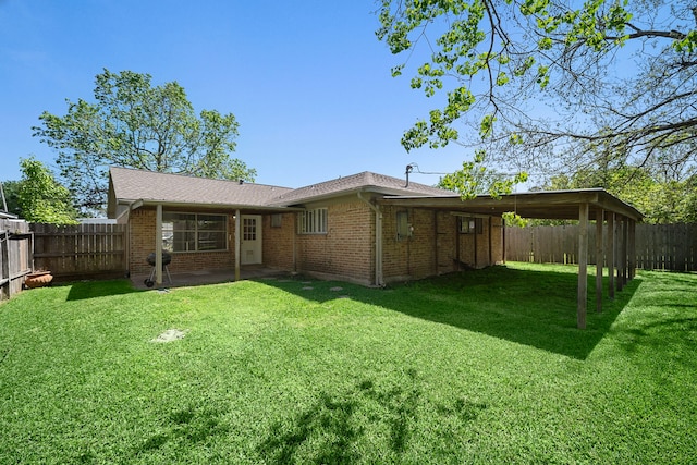 rear view of property featuring a carport, a patio, a lawn, brick siding, and a fenced backyard