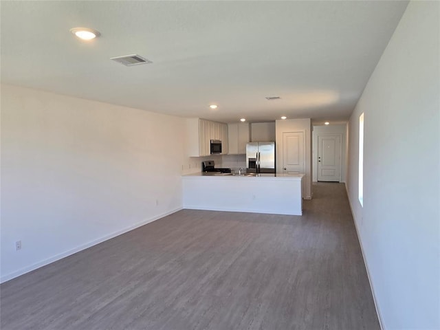 12426 Lady Slipper Rd, Houston, TX 77038 - kitchen with appliances with stainless steel finishes, dark wood-style flooring, a peninsula, baseboards, and open floor plan