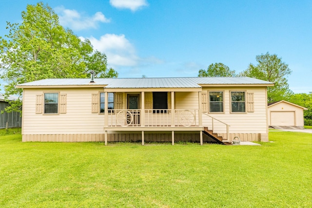 back of property with a yard, a detached garage, a porch, and metal roof