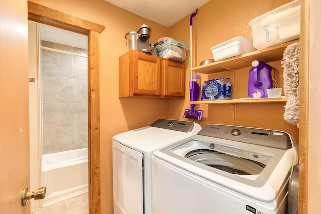 laundry room featuring washing machine and clothes dryer, light tile patterned floors, and cabinet space