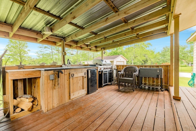 wooden deck with exterior kitchen, a sink, and a bar