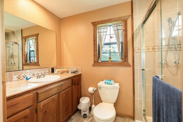 bathroom featuring toilet, backsplash, wood finished floors, a shower stall, and vanity