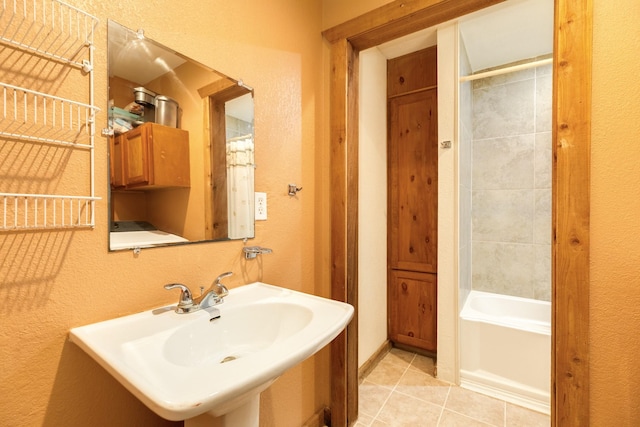 bathroom featuring a textured wall, tile patterned flooring, and a sink