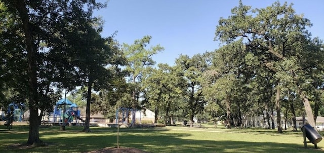 view of home's community featuring playground community and a yard