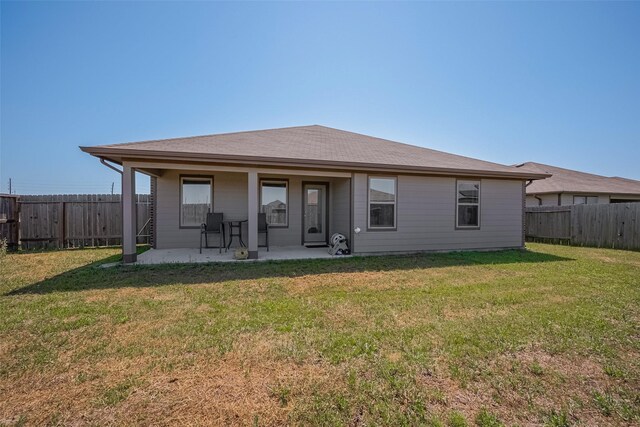 rear view of house featuring a yard, a fenced backyard, and a patio