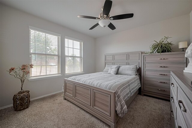 bedroom featuring a ceiling fan, light carpet, baseboards, and multiple windows