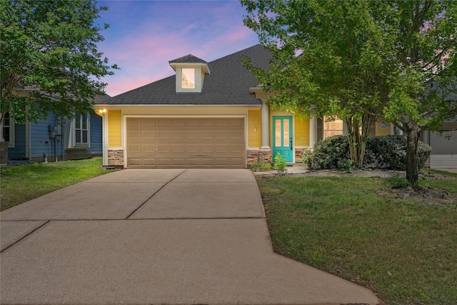 view of front of house featuring driveway, stone siding, an attached garage, and a front lawn