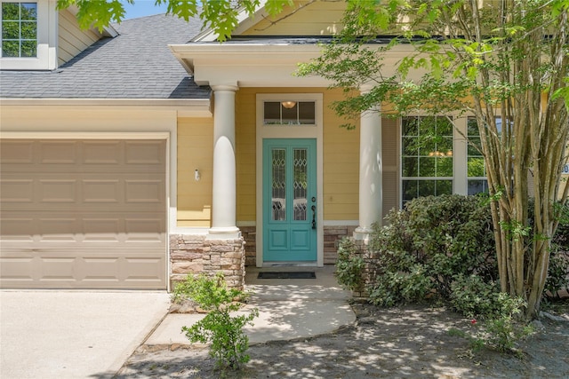 doorway to property featuring a shingled roof, stone siding, and a garage