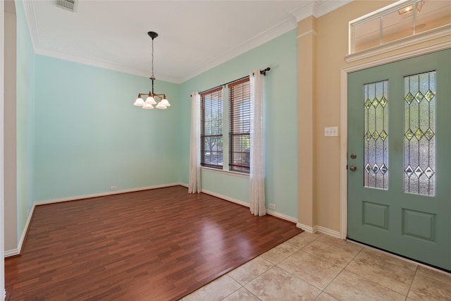 foyer entrance with ornamental molding, baseboards, a notable chandelier, and wood finished floors