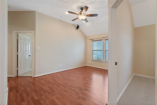 empty room with baseboards, vaulted ceiling, a ceiling fan, and wood finished floors