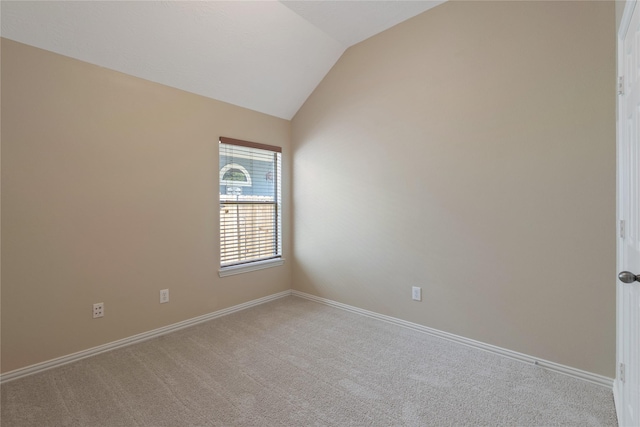carpeted spare room with baseboards and vaulted ceiling