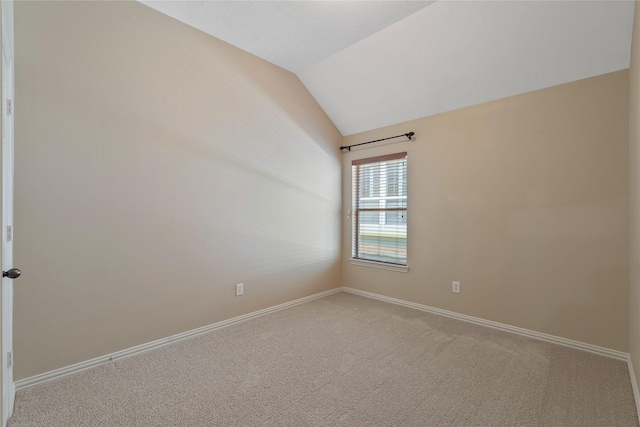 carpeted spare room with baseboards and vaulted ceiling