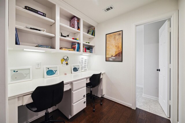 office area featuring built in desk, dark wood-style flooring, baseboards, and visible vents