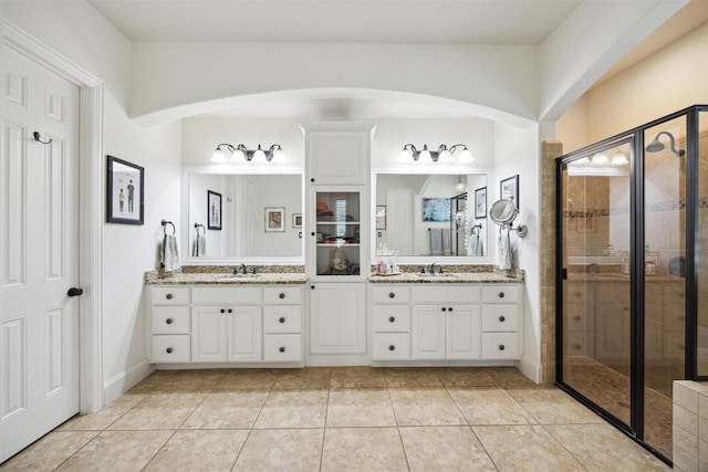 bathroom with a sink, tile patterned floors, double vanity, and a stall shower