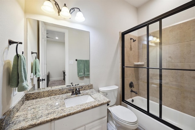 bathroom featuring enclosed tub / shower combo, vanity, and toilet