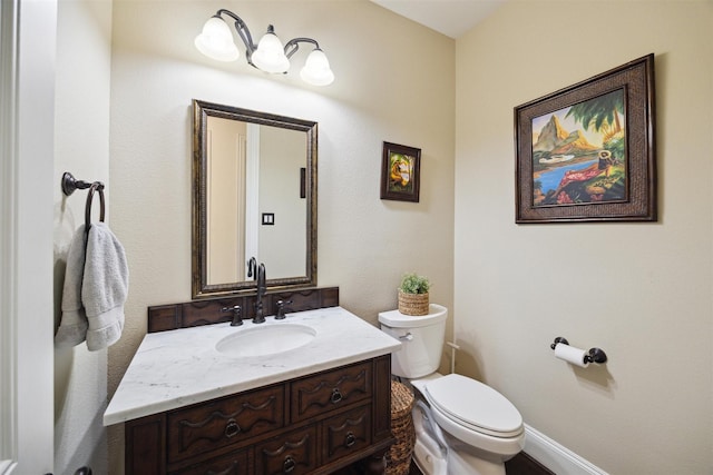 half bath with toilet, vanity, and baseboards