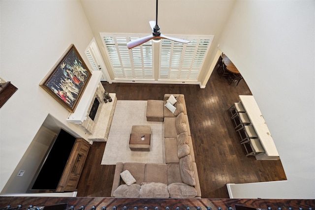 living room with a ceiling fan, a high ceiling, and wood finished floors