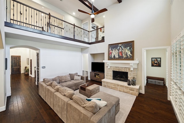 living area with arched walkways, a high ceiling, ceiling fan, and dark wood-style floors
