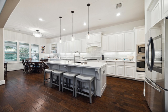 kitchen with dark wood-type flooring, white cabinets, appliances with stainless steel finishes, light countertops, and a sink