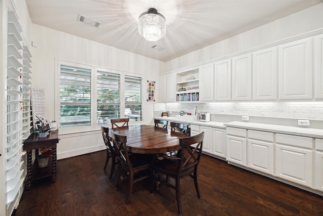 dining space with dark wood-style flooring, a notable chandelier, and visible vents