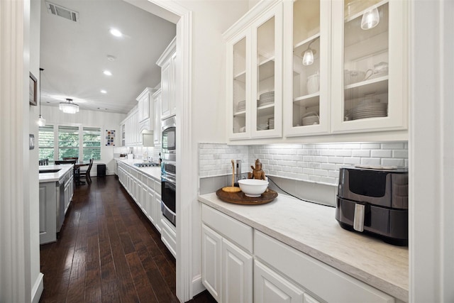 kitchen with white cabinetry, glass insert cabinets, visible vents, and stainless steel appliances