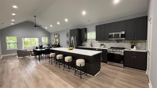 15016 Indian Hill Trl, Willis, TX 77378 - kitchen with appliances with stainless steel finishes, ceiling fan, a breakfast bar area, light countertops, and a center island