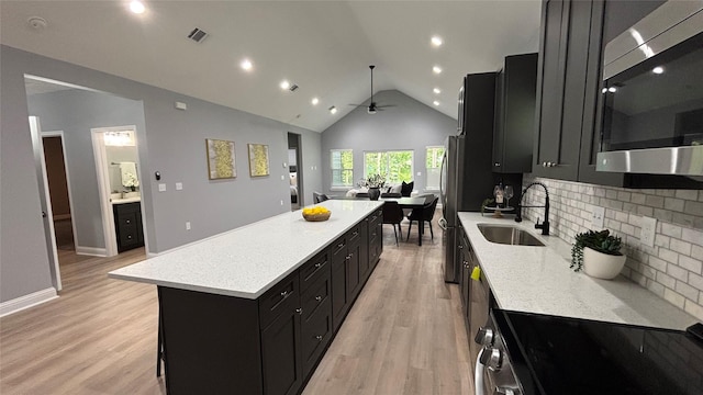 15016 Indian Hill Trl, Willis, TX 77378 - kitchen with dark cabinetry, appliances with stainless steel finishes, a large island, ceiling fan, and lofted ceiling