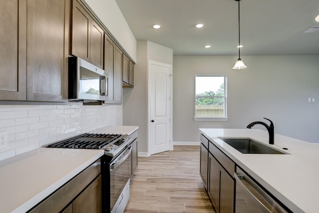 1613 Mija Park Rd, Seabrook, TX 77586 - kitchen featuring appliances with stainless steel finishes, light countertops, light wood-style floors, decorative backsplash, and a sink