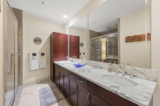 bathroom featuring a shower stall, tile patterned floors, a sink, double vanity, and baseboards