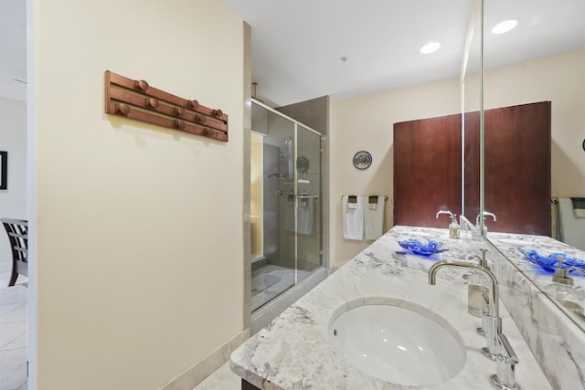 full bath with a shower stall, baseboards, a sink, and double vanity