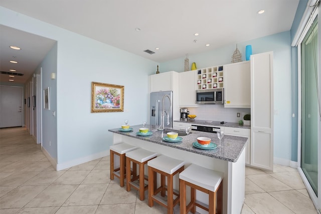 kitchen with visible vents, a sink, light tile patterned floors, decorative backsplash, and appliances with stainless steel finishes